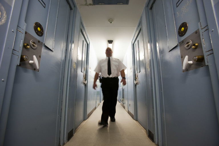 A prison officer walks along a corridor in Send prison