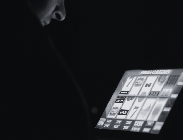 Black and white image of person gambling online on a laptop.