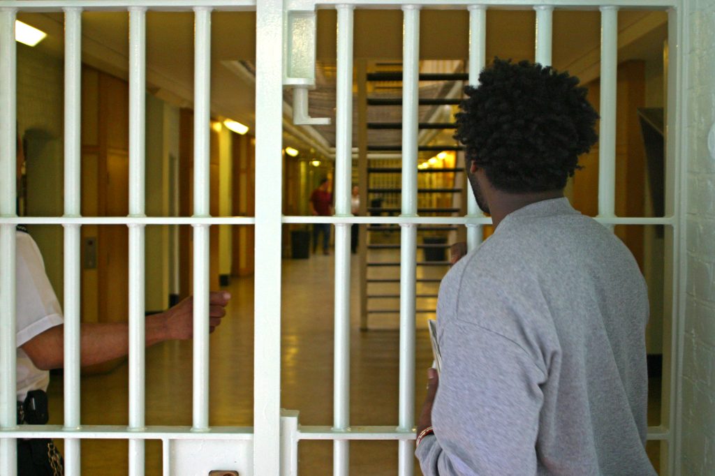 A prisoner waits to be let through an internal security gate buy a prison officer on D wing. HMP Wandsworth, London, United Kingdom