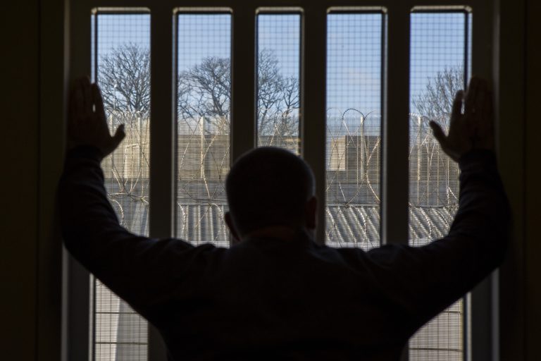 A prisoner staring out of a window down one of the corridors of the enhanced wing at HMP/YOI Portland, Dorset, United Kingdom.