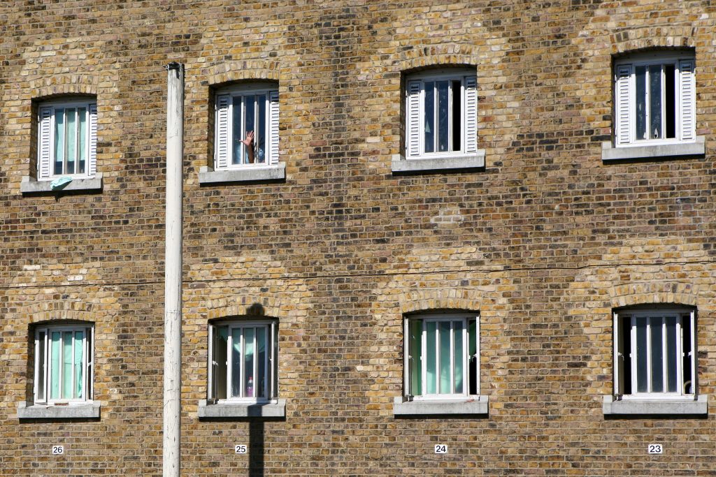 A hand waves from a cell window of D wing Wandsworth Prison.